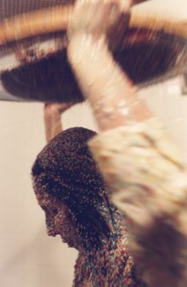 A foto mostra a artista performática Márcia X durante sua obra "Pancake" onde ela se cobre com leite moça e granulados coloridos