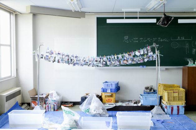 Fotografias resgatadas são penduradas para secar em uma sala de aula