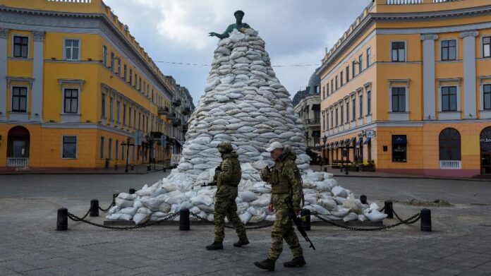 Soldados caminham por monumento coberto por sacos de areia em Odessa, na Ucrânia, em meio à invasão da Rússia. Foto: Alexandros Avramidis/Reuters