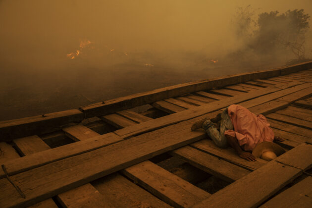 Voluntário procura focos de incêndio sob uma ponte de madeira na estrada Transpantaneira, no Pantanal de Mato Grosso. A estrada, que conta com 120 pontes, a maioria delas de madeira, é o único acesso à comunidade de Porto Jofre e a diversas fazendas da região. Poconé, Mato Grosso, 2020. Foto: Lalo de Almeida.