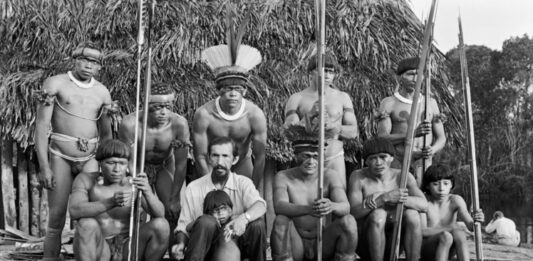 Image dialogue Standing, in the center, wearing a headdress, Mapukayaka Yawalapiti. Seated, from left to right, Sariruá Yawalapiti and Orlando Villas-Bôas. ç. 1955. Photo: Henri Ballot / Instituto Moreira Salles Collection/Henri Ballot Archive
